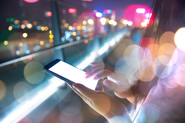 Hand holding mobile phone at night street