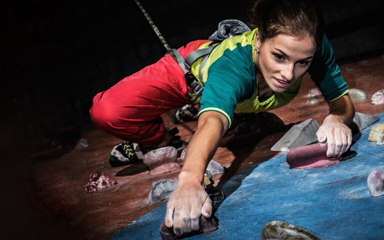 Young woman practicing rock-climbing on a rock wall indoors