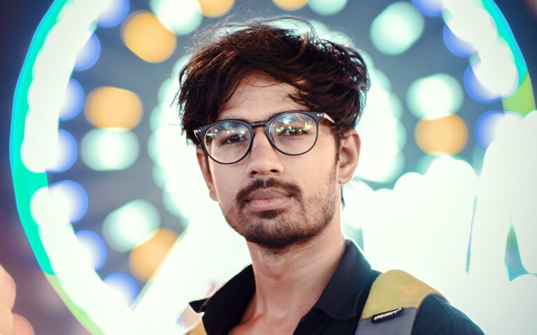 Portrait Of Confident Young Man At Illuminated Amusement Park